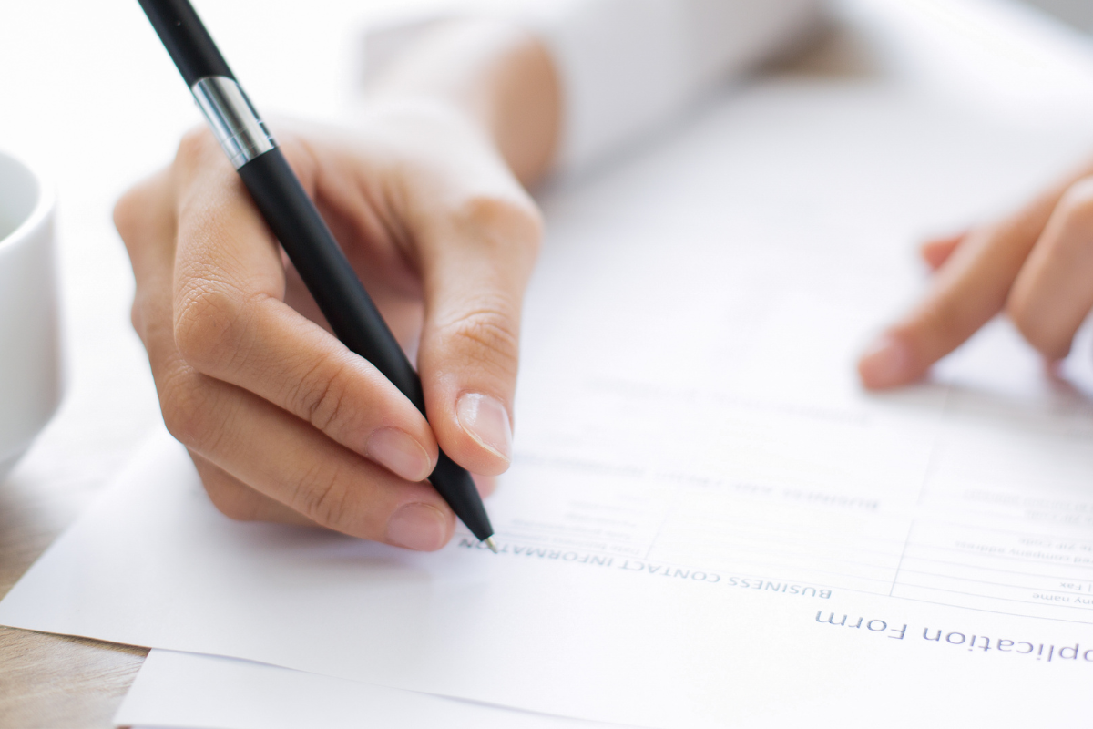 A person writing on pad of paper.